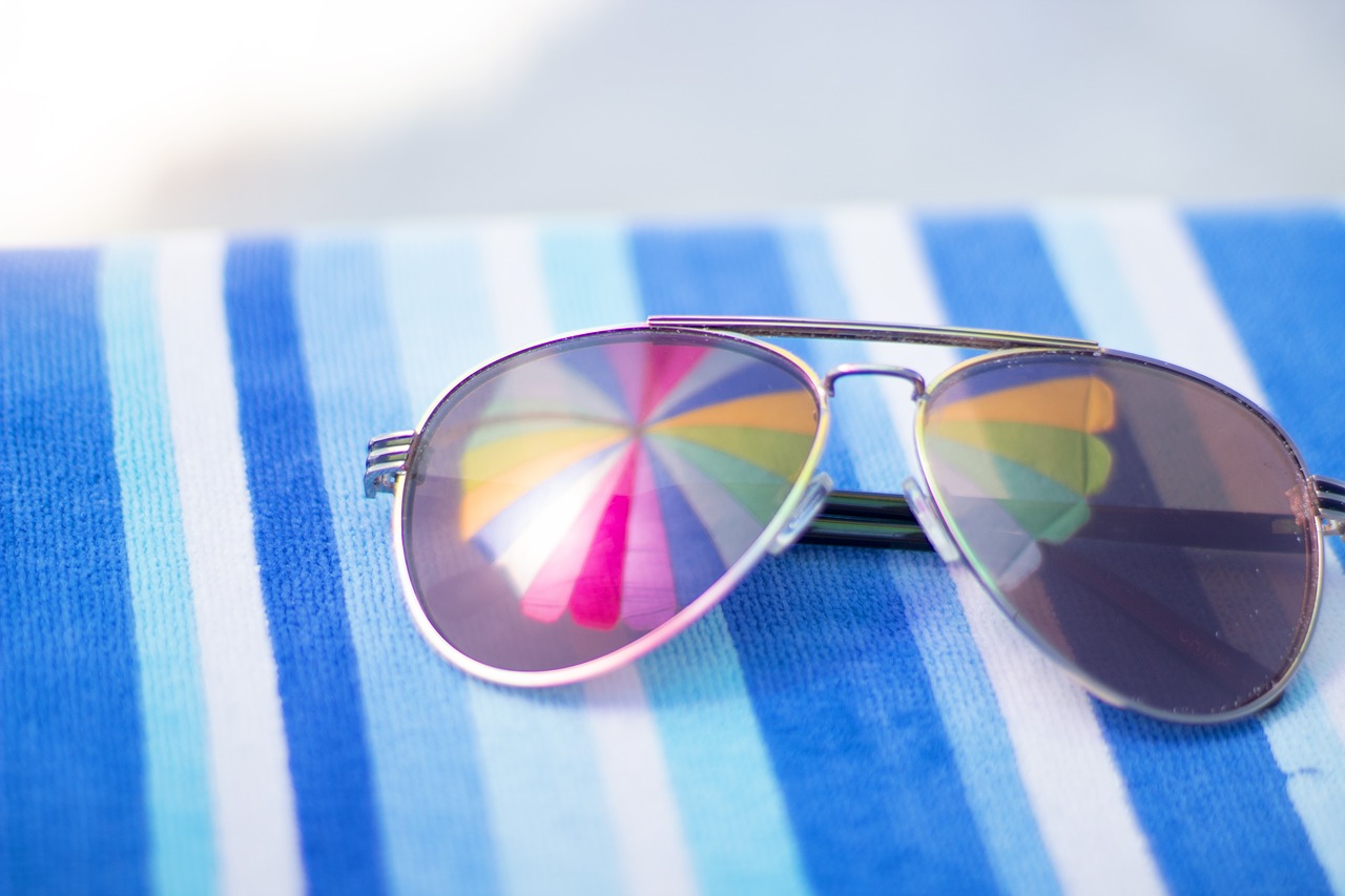 Sunglasses resting on a blue striped towel by the pool