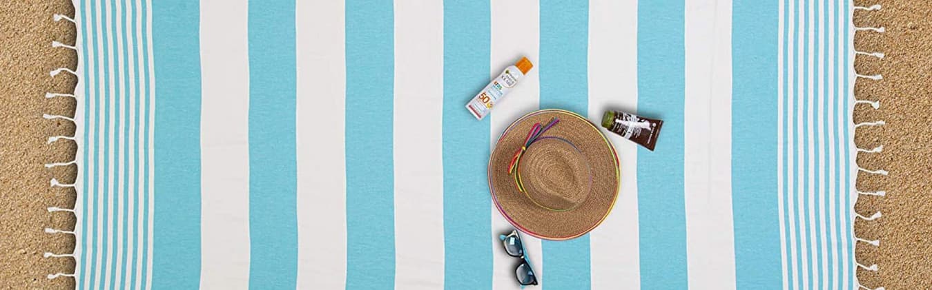 Striped Turkish beach towel with fringe on a sandy beach