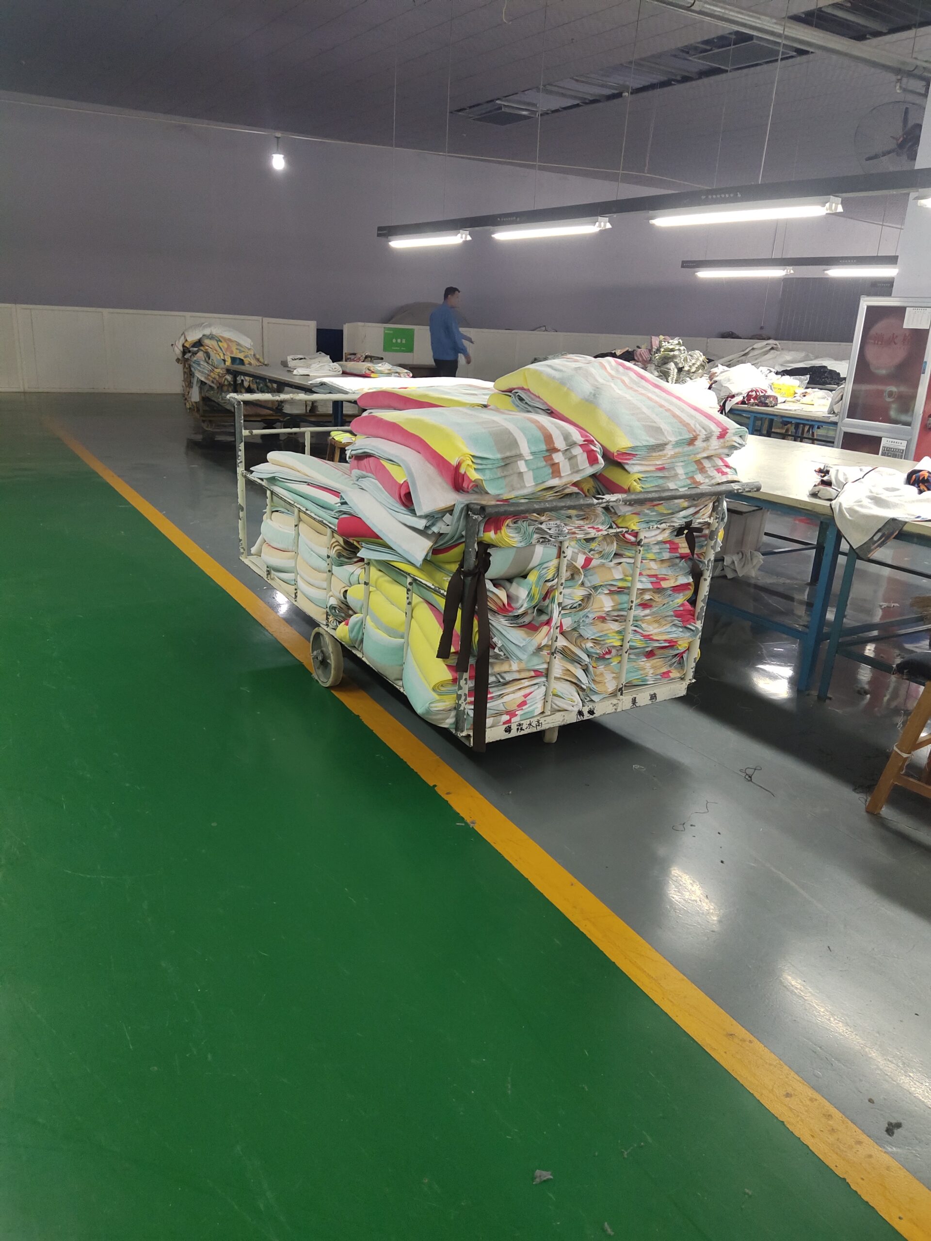 Stacks of striped cotton beach towels on a trolley in the finishing workshop