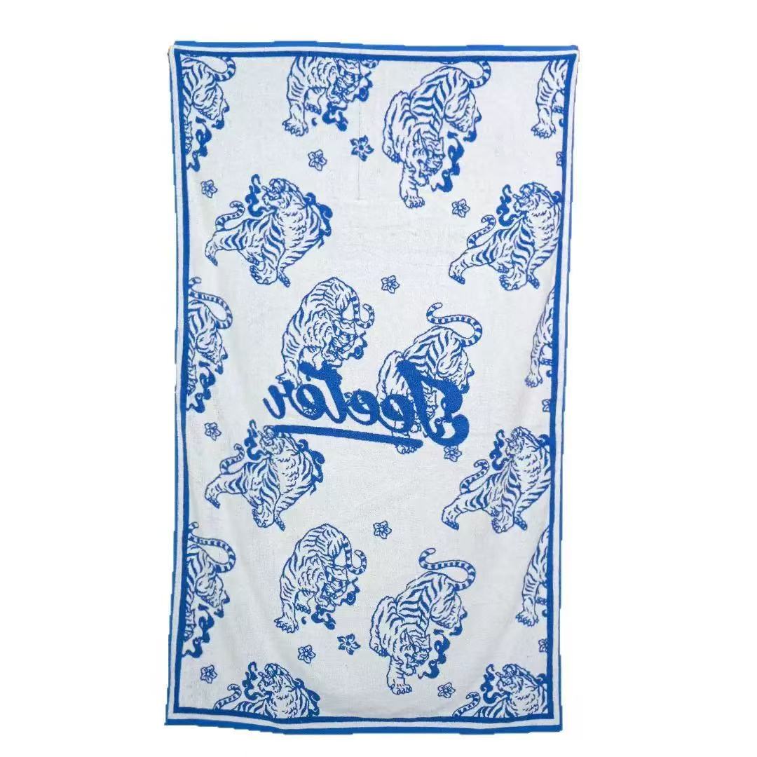 White and blue jacquard cotton beach towel with woven tiger motifs and a blue border
