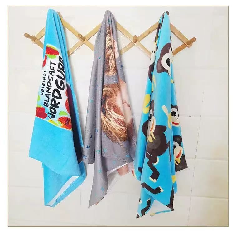 Three colorful printed cotton velour beach towels hanging from a wooden rack